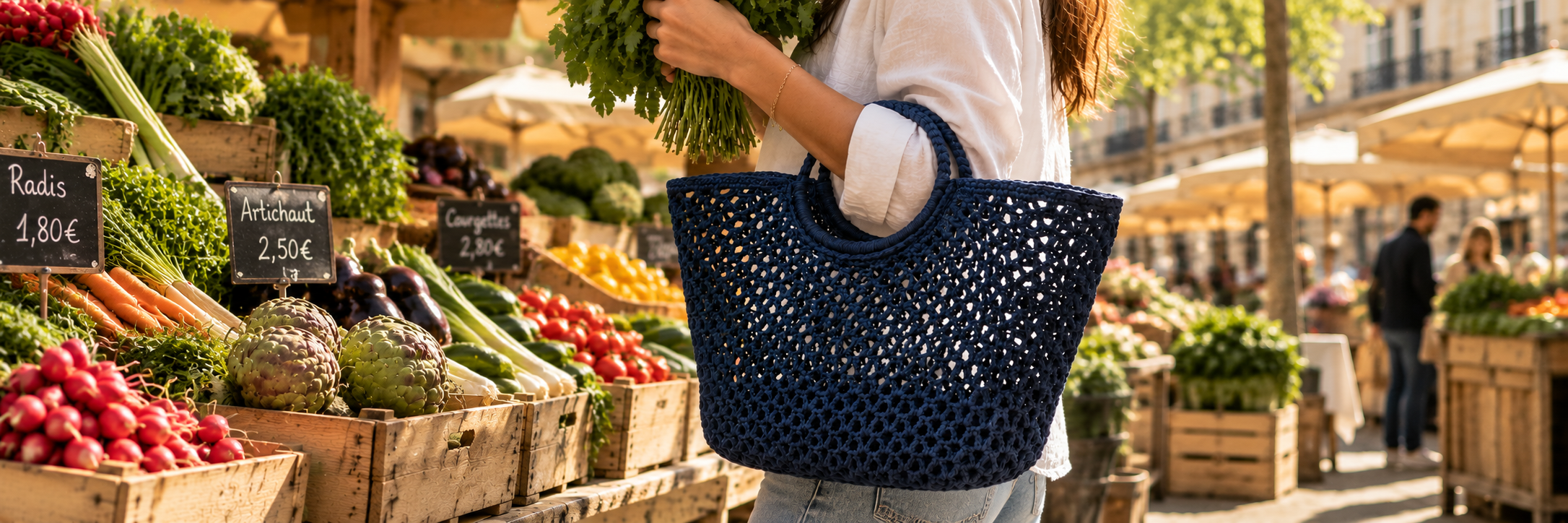 Woman carrying the Rosie indigo crochet basket bag at a sunny French farmers' market