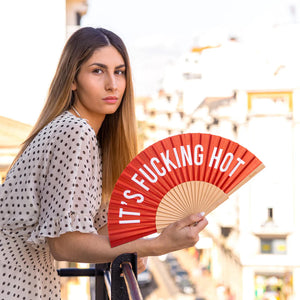 Fun Fisura hand fan shown open with printed design "it's fucking hot" in Red