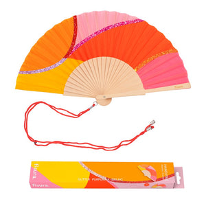 Fisura hand fan shown open, featuring  waves of Pink and Orange design on bamboo ribs with a cord