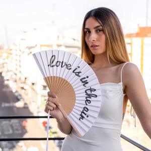 Fisura hand fan shown open with printed design "Love is in the air".
