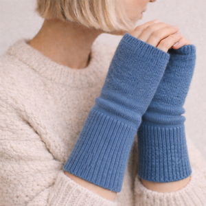 Woman wearing fingerless knit mittens in blue 