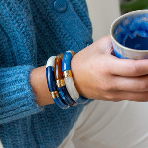 Parabaya resin bangle bracelets stacked on wrist, blue and neutral tones with gold-plated details