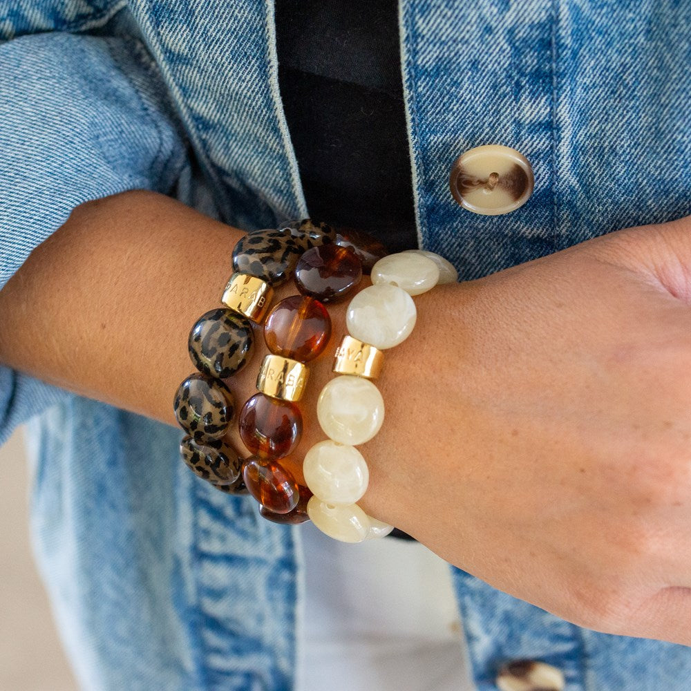 Parabaya Bombom resin bangle bracelets stacked on wrist, featuring leopard motif in hazelnut, and glossy amber, cream tones