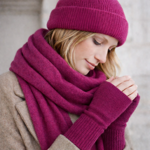 Woman wearing fingerless knit mittens, beanie and scarf in raspberry