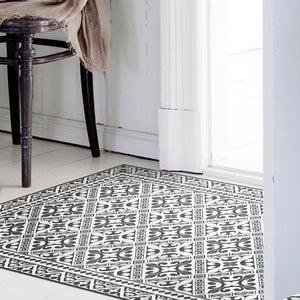 Beija Flor vinyl rug Flor De Lis Black&White placed on the floor in a styled indoor setting.
