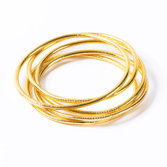 Light gold thin Buddhist bangles stacked together, flexible waterproof bracelets with gold leaf, a symbol of good luck