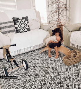 Beija Flor vinyl rug Flor De Lis Black & White placed on the floor in a styled indoor setting.
