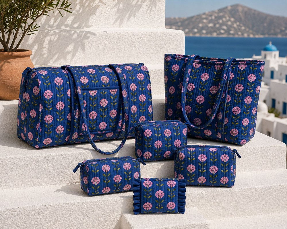 VOYAGE Tali navy and pink floral set of 3 pouches with matching weekender and tote on a sunny Mediterranean terrace