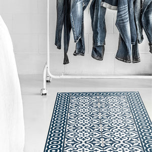 Beija Flor vinyl rug 'Mountain-Indigo' under clothes rack in a styled interior space.